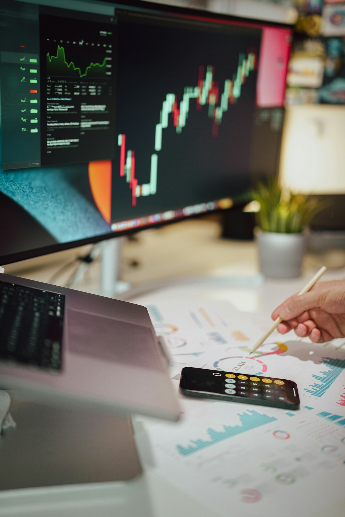 Person reviewing printed charts beside a computer monitor while building a B2B prospecting list