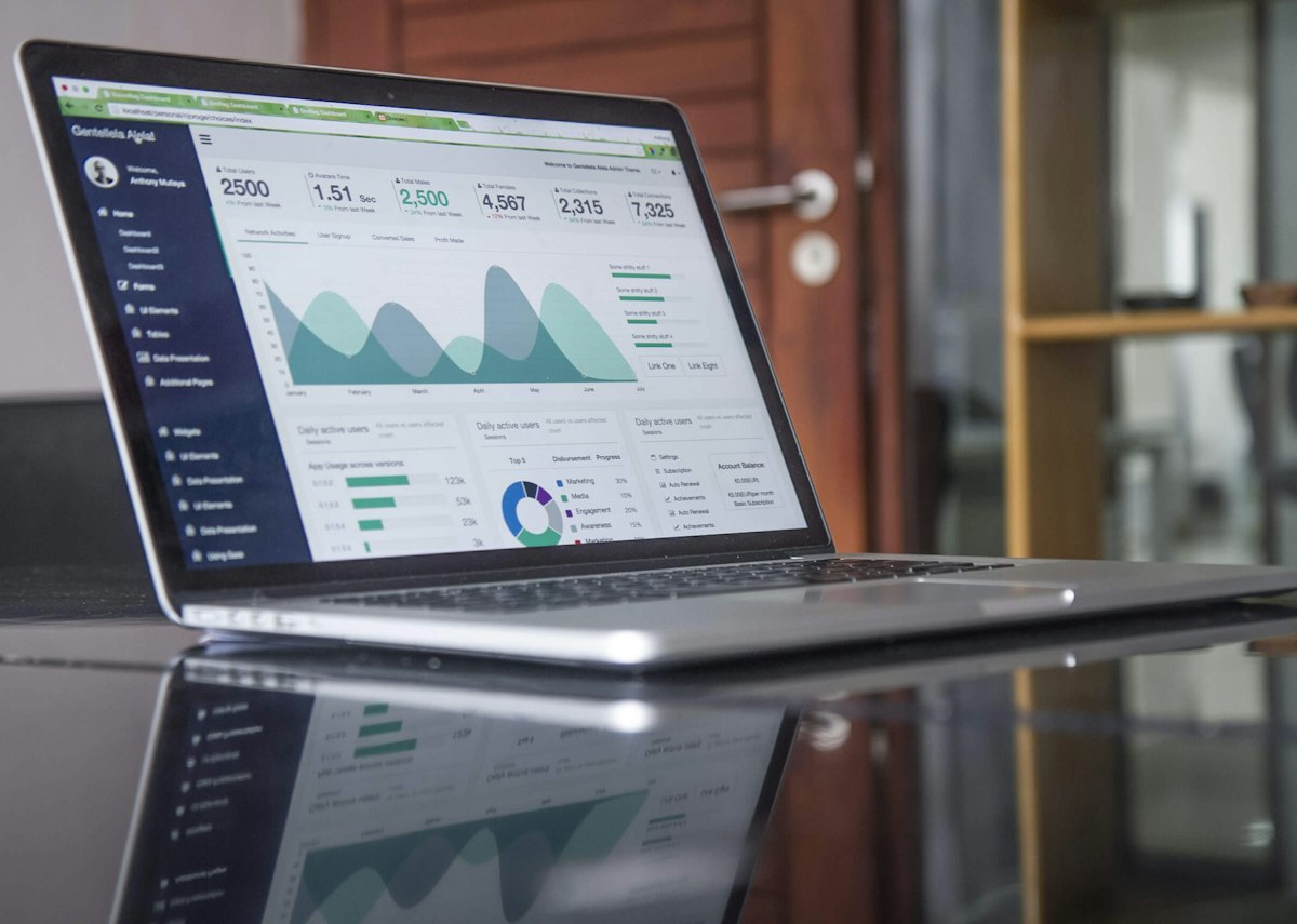 Laptop on a desk showing a business data dashboard with charts and company metrics